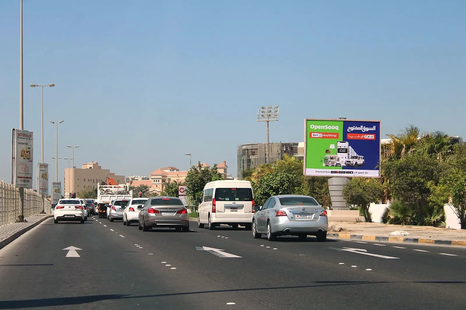 An OpenSooq billboard beside a queue of traffic on a road in Bahrain
